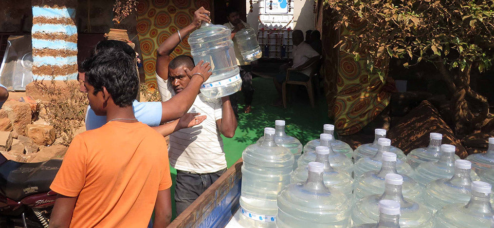Männer heben Wasserkanister in einem Außenbereich an.