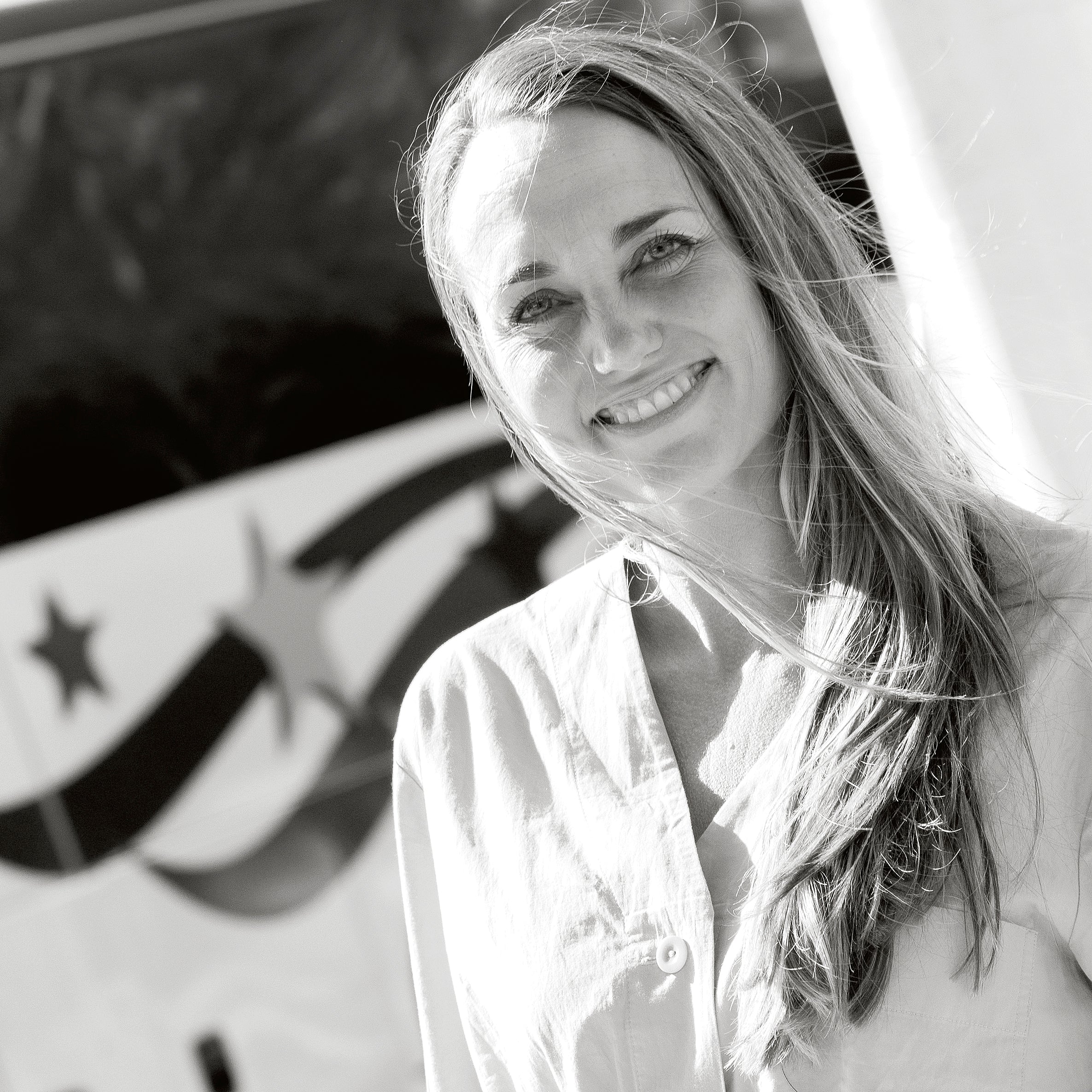 Frau mit langem Haar lächelt, im Hintergrund Sterne und Streifen.